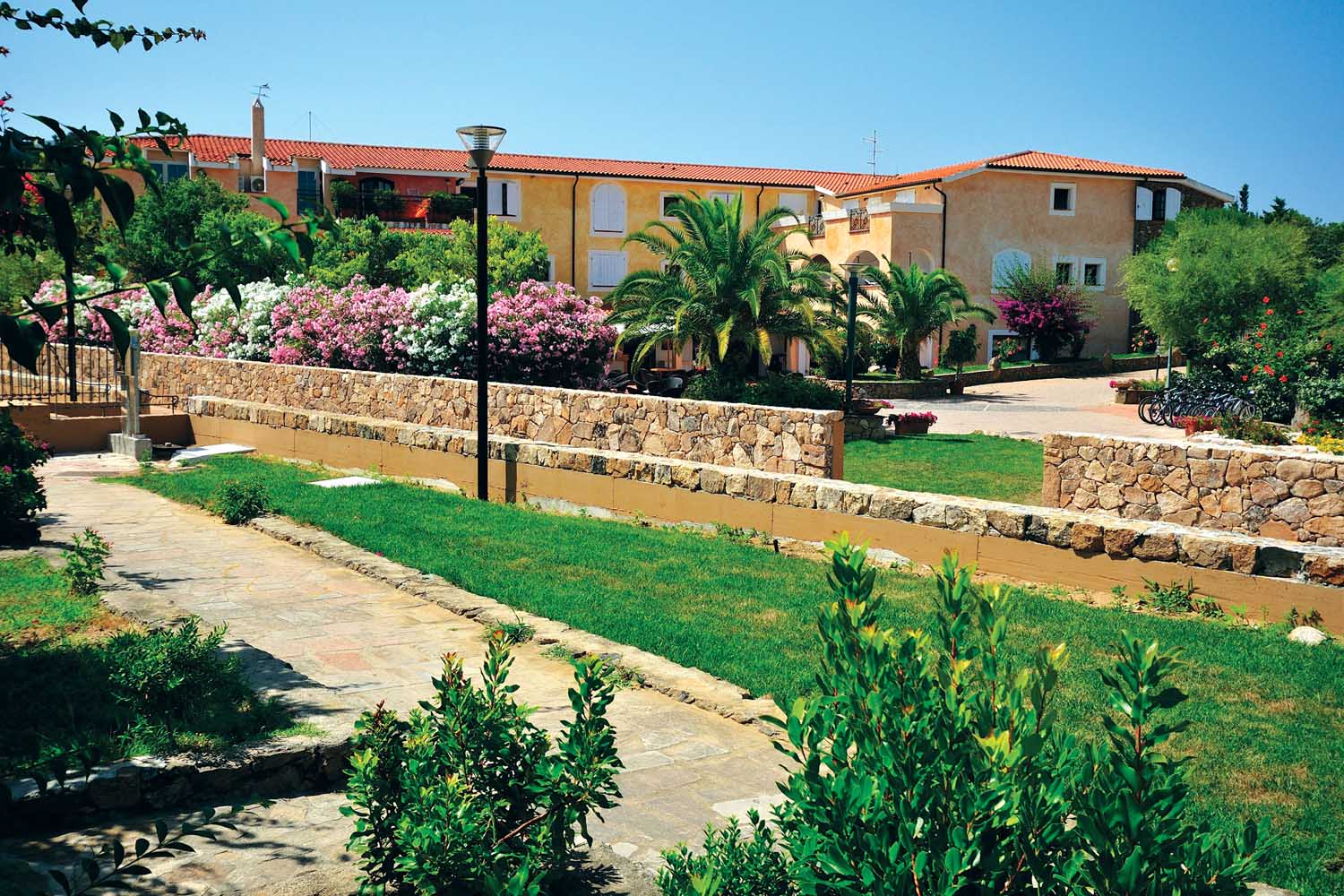 Piante, giardini curati, arbusti e fiori tipici della macchia mediterranea caratterizzano gli esterni dell'Hotel Eurovillage di Budoni