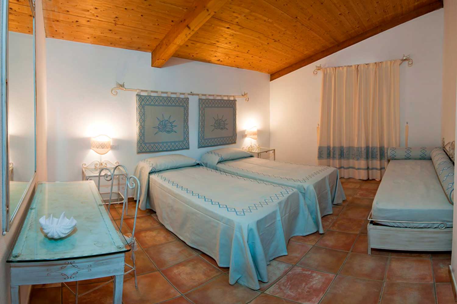 Esempio di una camera tripla del Villaggio Marina Rey di Costa Rei, finemente arredata in stile sardo.