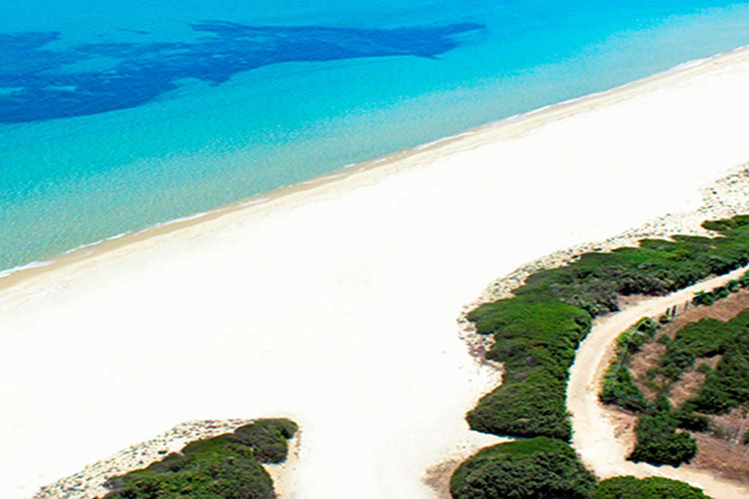 Panoramica dall'alto della spiaggia di sabbia bianca e mare cristallino al Marina Rey Beach Resort